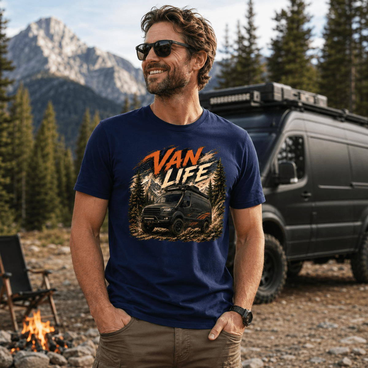 Man wearing a 'Van Life' t-shirt in a mountainous outdoor setting with a van and campfire.