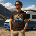 Man wearing a 'Van Life' t-shirt with a camper van graphic, standing in front of a camper van and mountainous landscape.