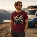 Man wearing a 'Van Life' t-shirt with a car graphic, standing in front of a scenic mountain landscape.