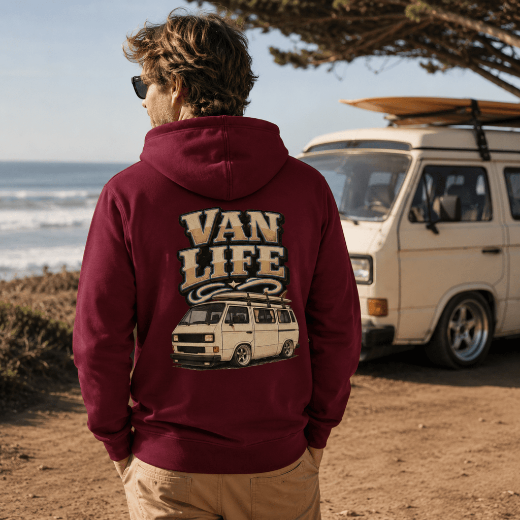 Person wearing a 'Van Life' hoodie by a van on a beach.