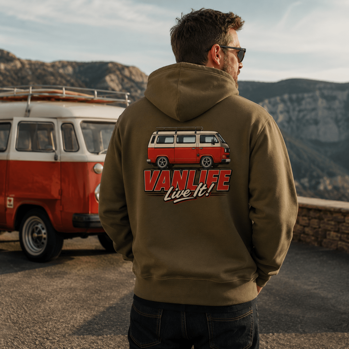 Model wearing Camberline olive van life hoodie showing VanLife Live It red and cream retro campervan side profile graphic on back