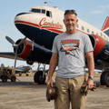 Man standing in front of a Camberline airplane wearing a branded t-shirt.