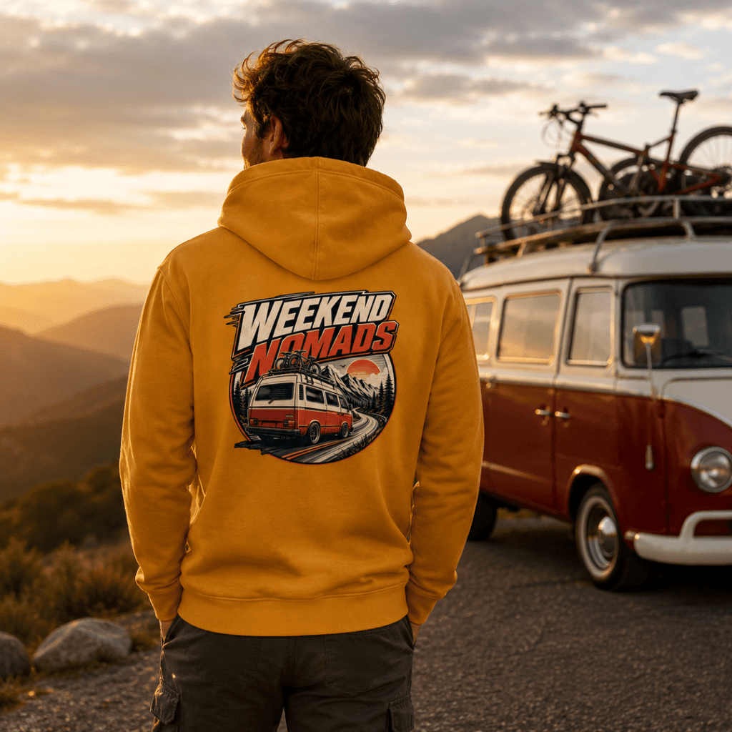 Model wearing Camberline amber/mustard van life hoodie showing Weekend Nomads rear-view retro van with bikes and mountain sunset badge on back
