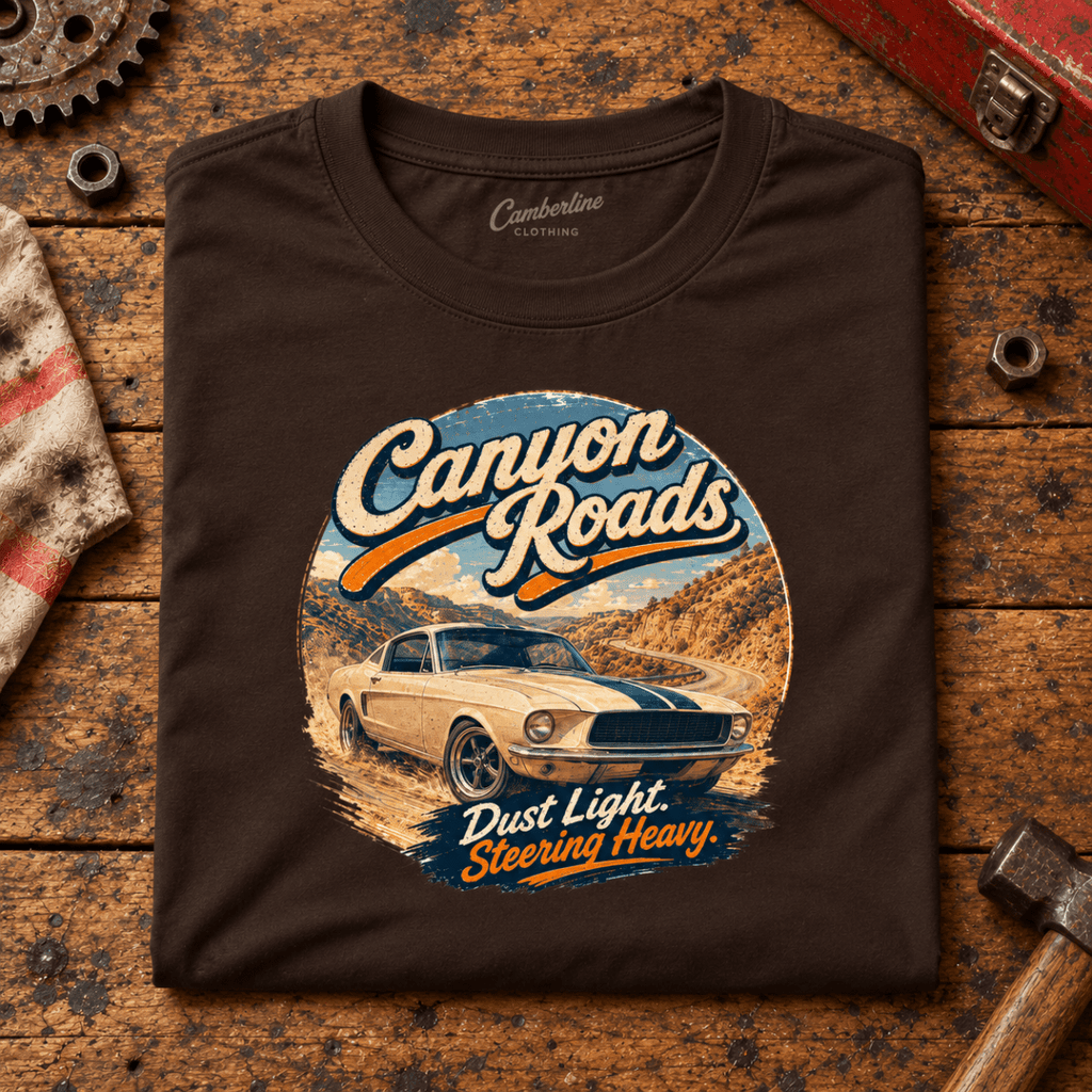 Canyon Roads Muscle Fastback American Drive Graphic T-Shirt — Dark Chocolate, folded front main hero on a worn automotive workbench – car-ts-0056