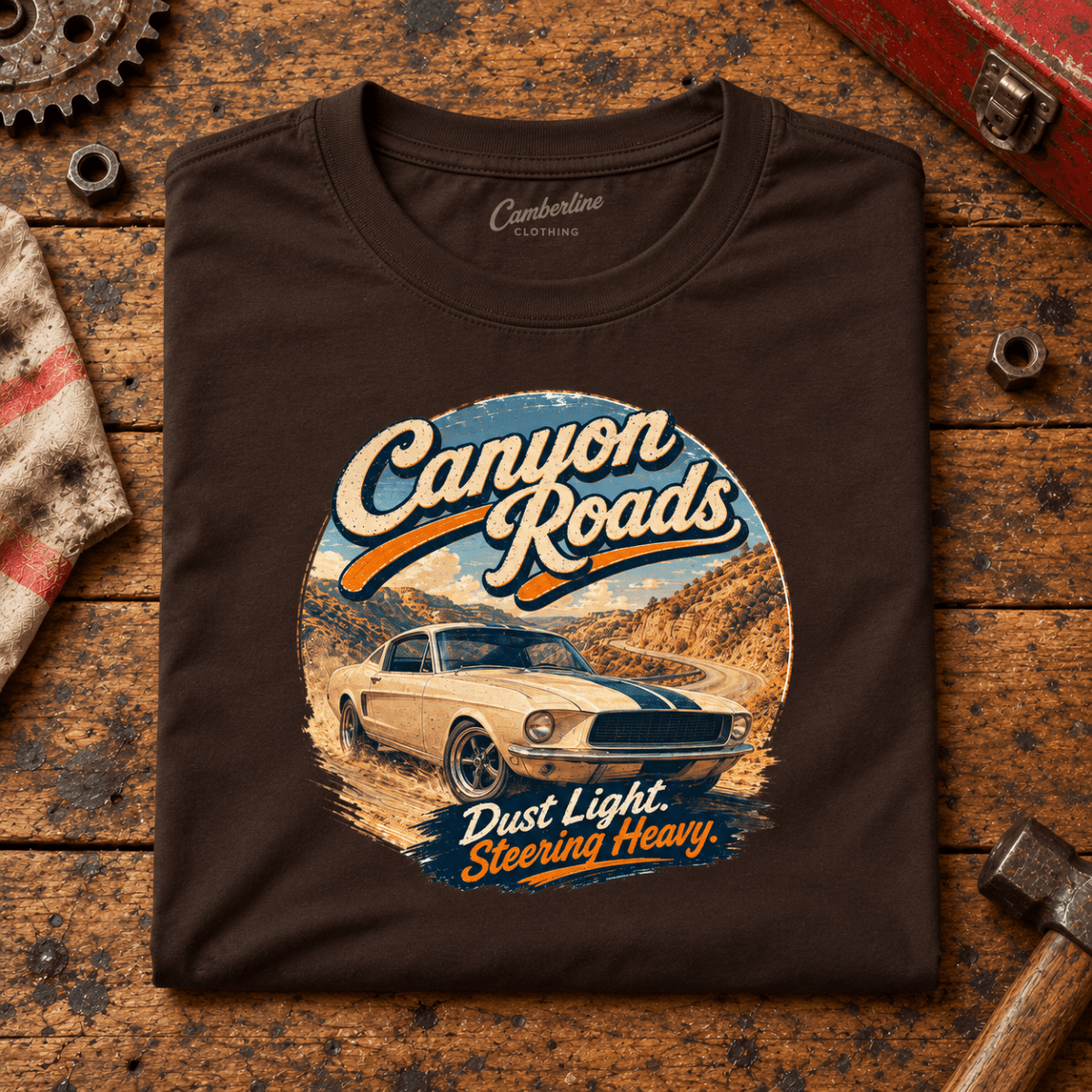 Canyon Roads Muscle Fastback American Drive Graphic T-Shirt — Dark Chocolate, folded front main hero on a worn automotive workbench – car-ts-0056