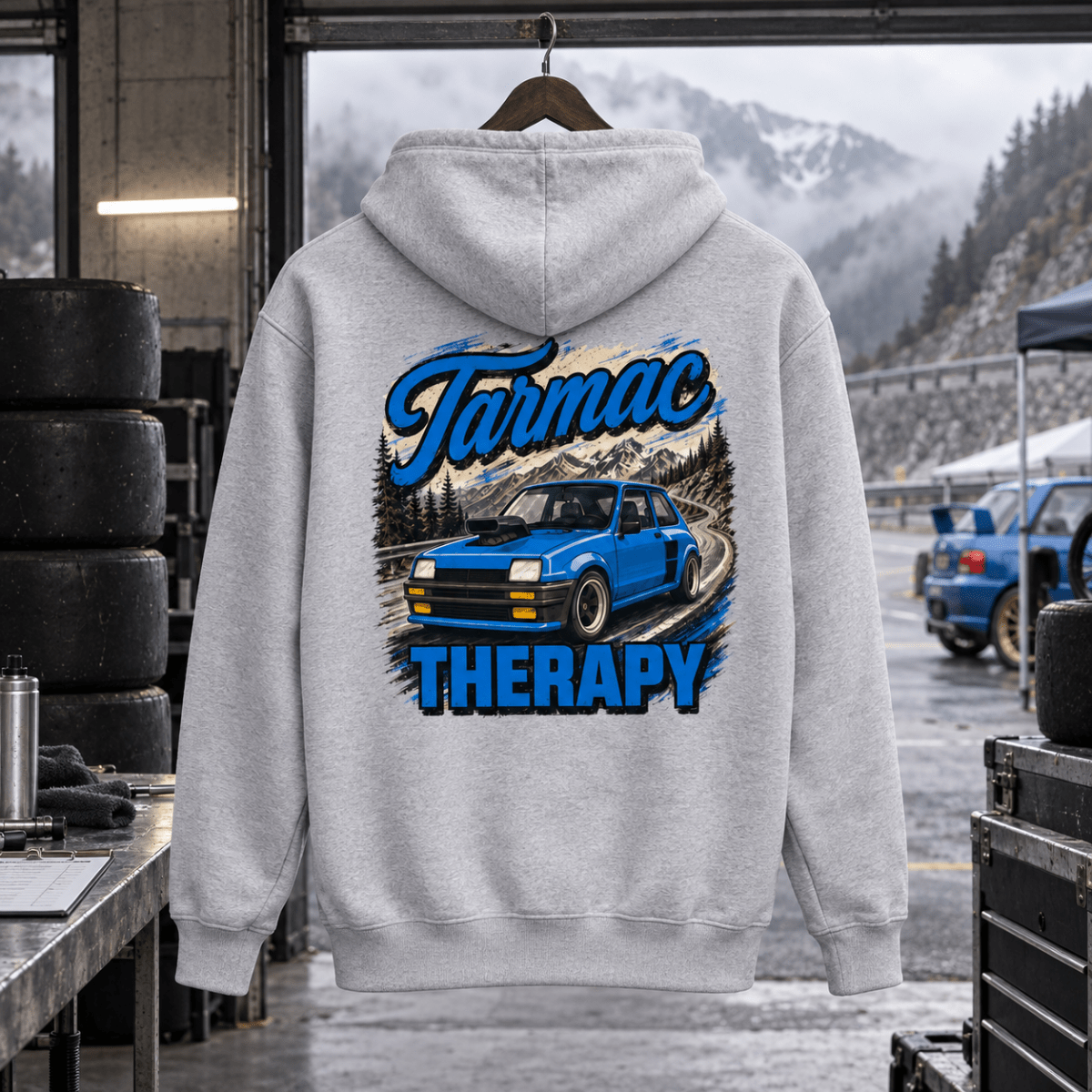 Tarmac Therapy light grey hoodie back in a gritty hill-climb service bay
