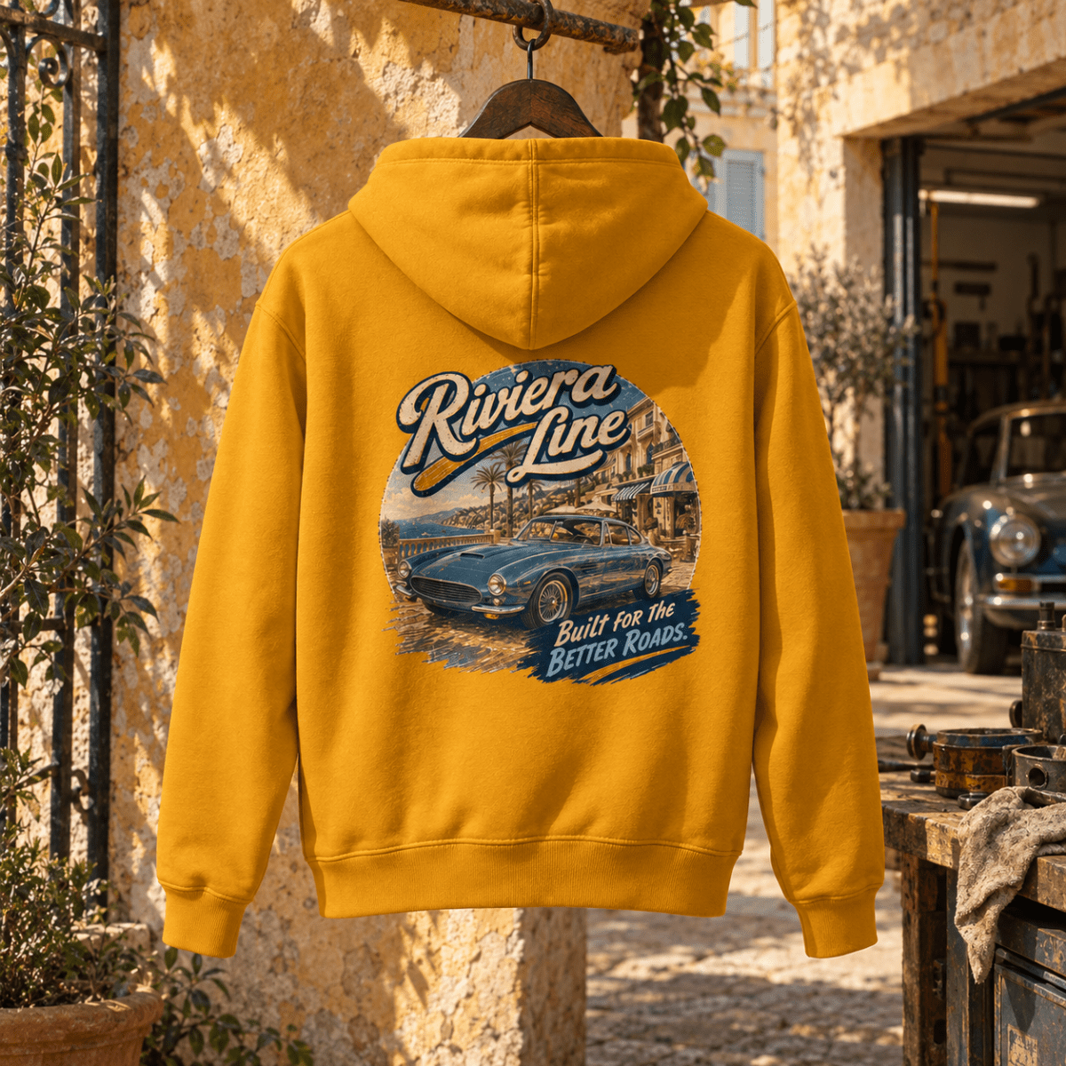 Riviera Line mustard hoodie back in a gritty Mediterranean courtyard
