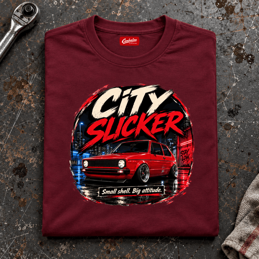 Camberline city slicker hot hatch burgundy T-shirt, folded front view on a workshop bench with the complete graphic visible.