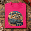 Cote D'Azur Classic GT French Riviera Graphic T-Shirt — Hot Pink, folded front main hero on a worn automotive workbench – car-ts-0055