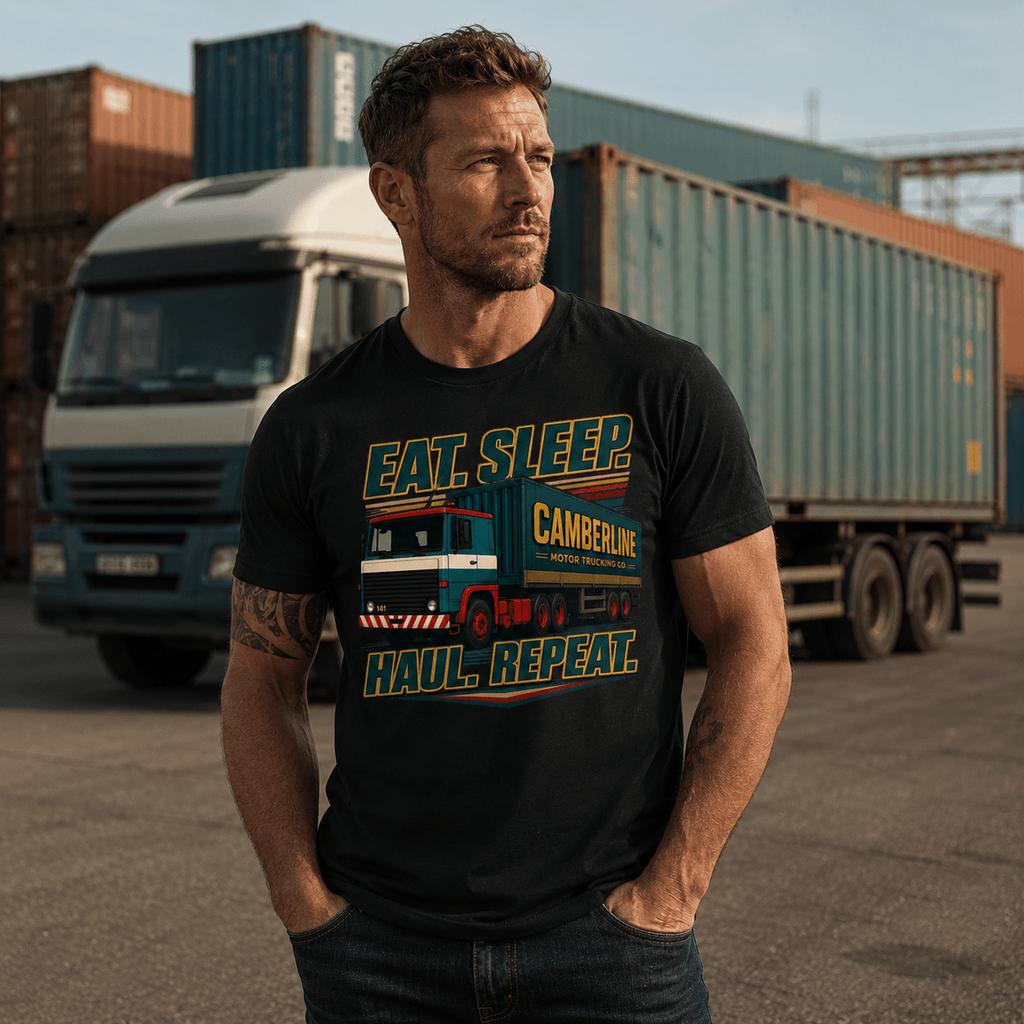 Male model wearing black Eat Sleep Haul Repeat Camberline lorry t-shirt standing in front of artic lorry and shipping containers at a container yard