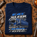 Navy chrome Eat Sleep Haul Repeat lorry T-shirt folded on a custom-truck workshop bench