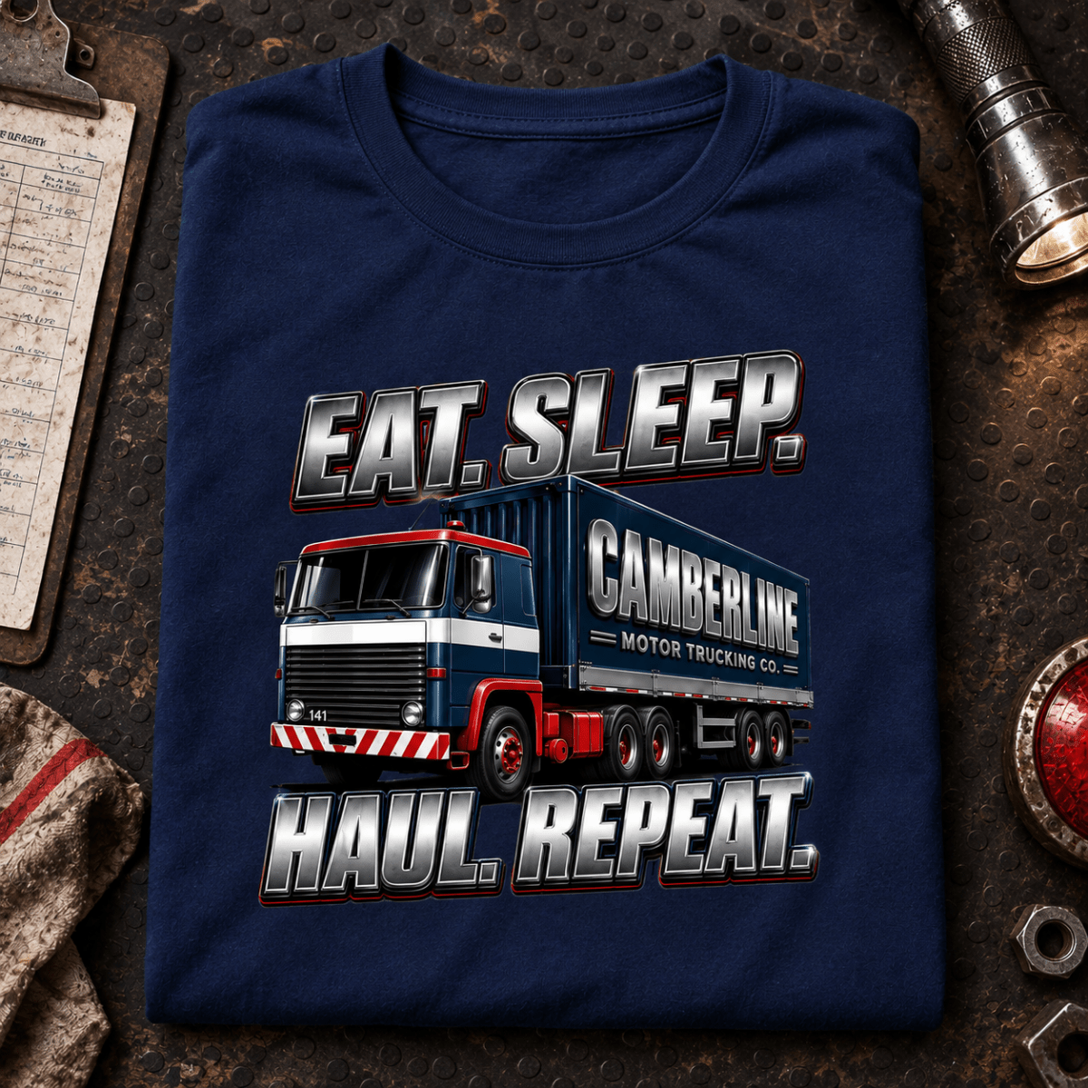 Navy Eat Sleep Haul Repeat lorry T-shirt folded on a gritty night depot desk