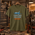 Military green Fighting Falcon aircraft graphic T-shirt in a gritty aviation workshop