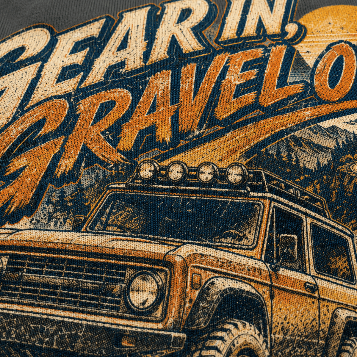 Close-up of a graphic print featuring a vintage off-road vehicle and large distressed text reading 'Gear in, Gravel out' in orange, beige, and dark blue tones.