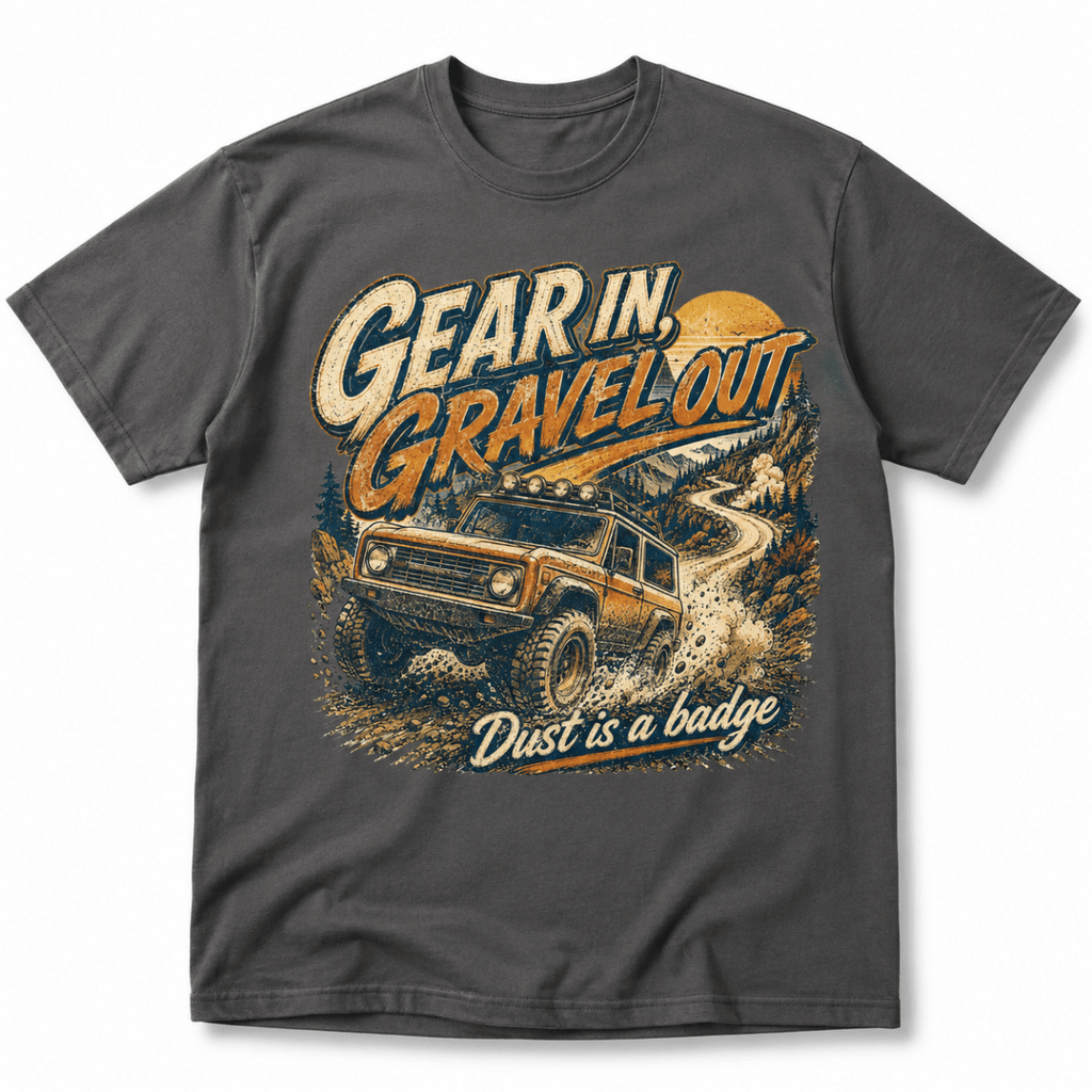 A dark gray crewneck t-shirt featuring a vintage-style graphic of an off-road vehicle on a dirt road with the text 'Gear in, Gravel out.' and 'Dust is a badge'.
