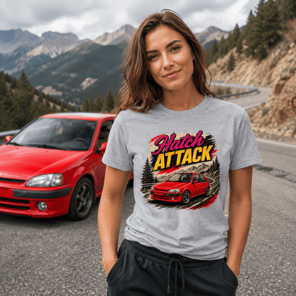 Woman wearing a 'Hatch Attack' t-shirt with a red car graphic, standing in front of a red car on a mountain road.