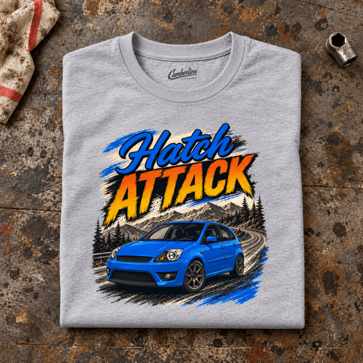 Hot Hatch Graphic T-Shirt – Hatch Attack Modern Performance, folded front main hero on a worn automotive workbench – car-ts-0014
