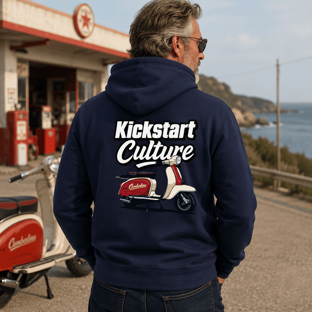 Man wearing a navy hoodie with 'Kickstart Culture' text and scooter graphic, standing by a vintage gas station.