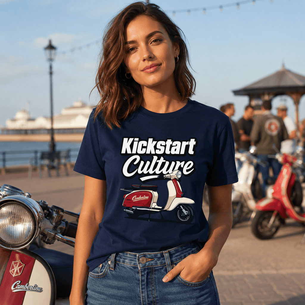 Woman wearing a navy blue t-shirt with 'Kickstart Culture' design, standing outdoors near scooters.