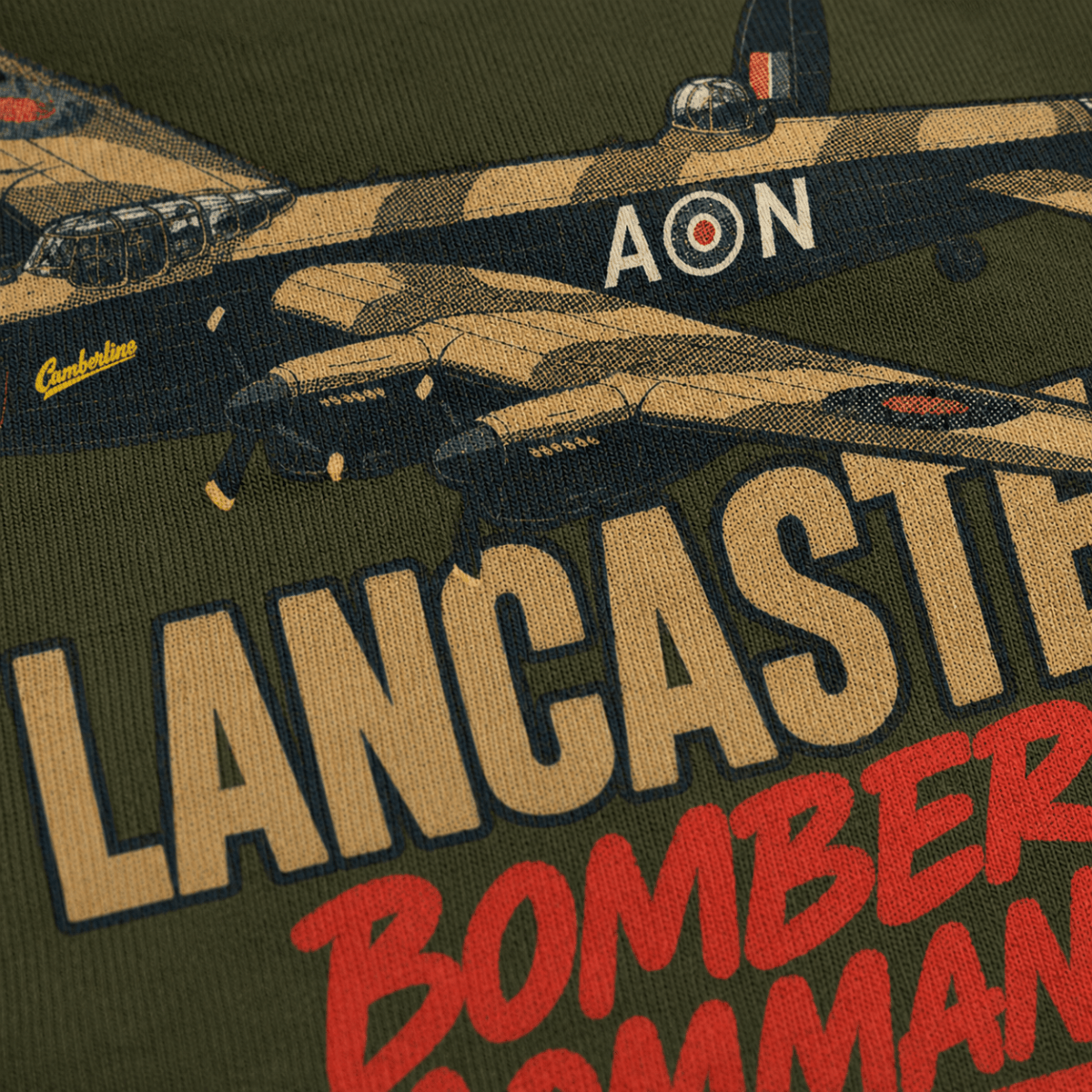Close-up of a graphic print on an olive green garment featuring a vintage Lancaster bomber in camouflage with large tan and red text reading 'LANCASTER' and 'BOMBER COMMAND'.