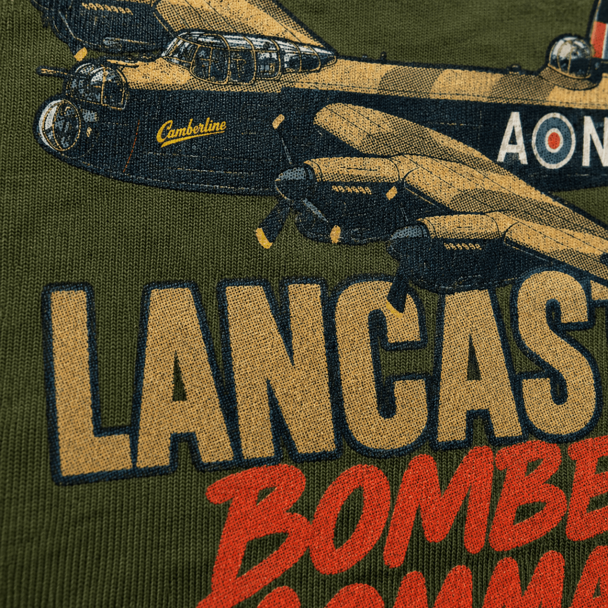 Close-up of an embroidered graphic on a green fabric, showing a vintage Lancaster bomber aircraft in tan and black with the word 'Lancaster' in large tan letters and red 'Bomber' text below.