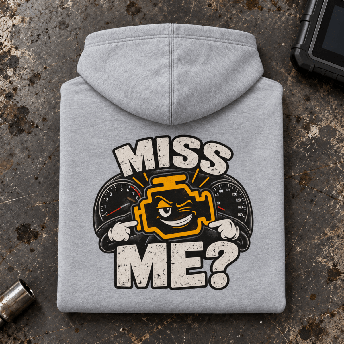 Camberline Check Engine Mechanic Hoodie in heather grey, folded back view on a workshop bench with full graphic visible