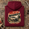 Camberline mud and manners 4x4 burgundy hoodie, folded rear view on a workshop bench with the complete graphic visible.