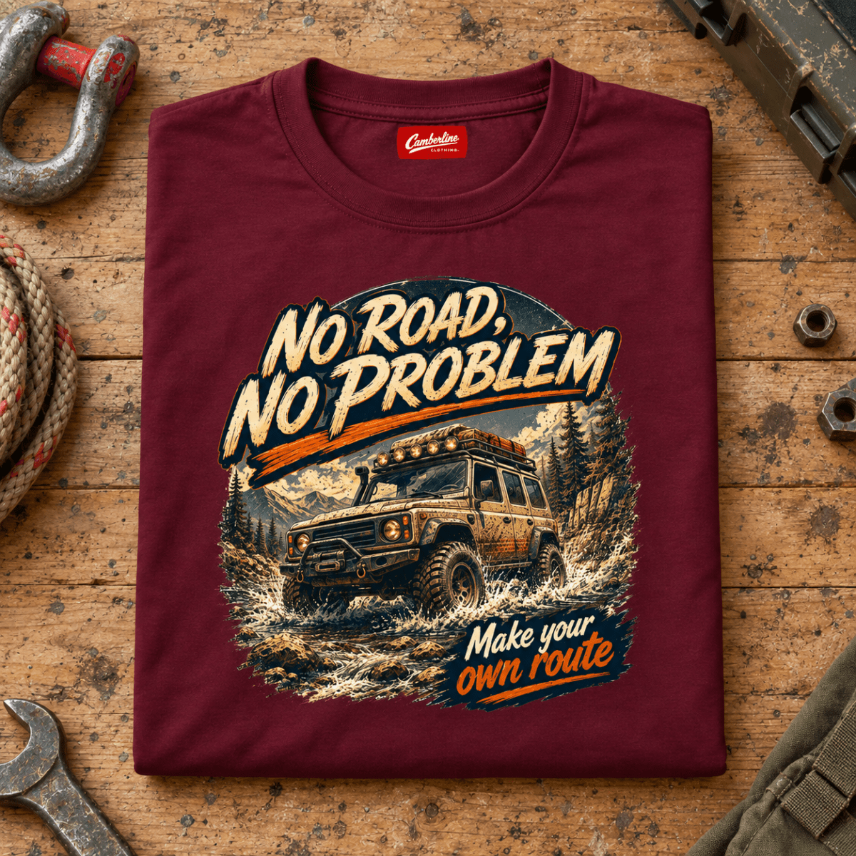 Folded maroon No Road No Problem Adventure T-shirt front on a workshop bench — car-ts-0090