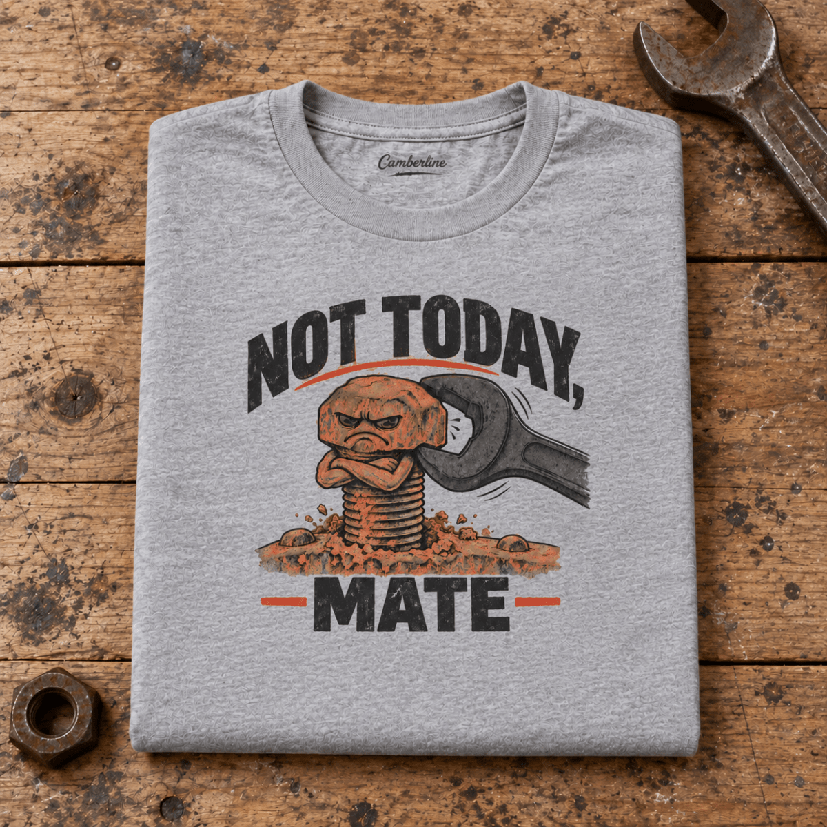 Camberline Stubborn Bolt Mechanic T-Shirt in heather grey, folded front view on a workshop bench with full graphic visible