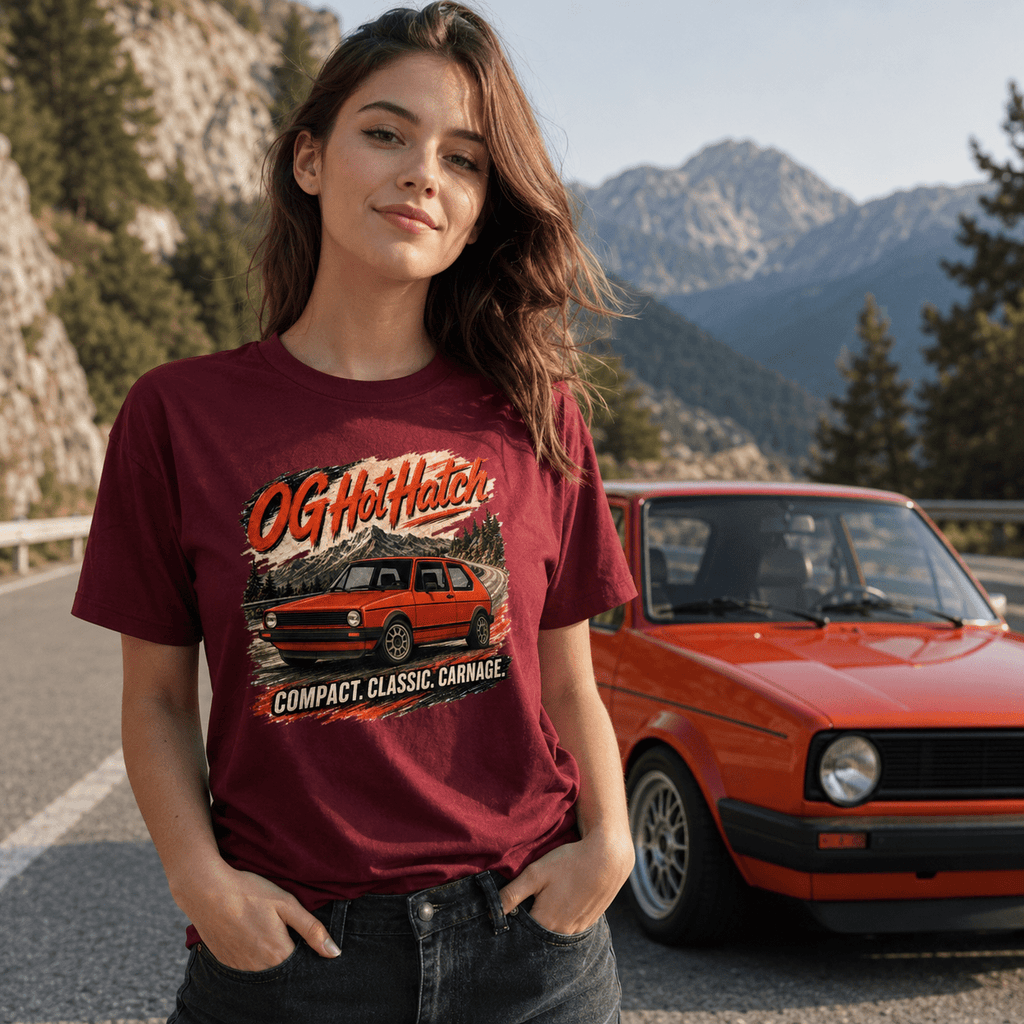 Woman wearing a maroon t-shirt with a graphic design of a red car, standing in front of a red car on a mountain road.