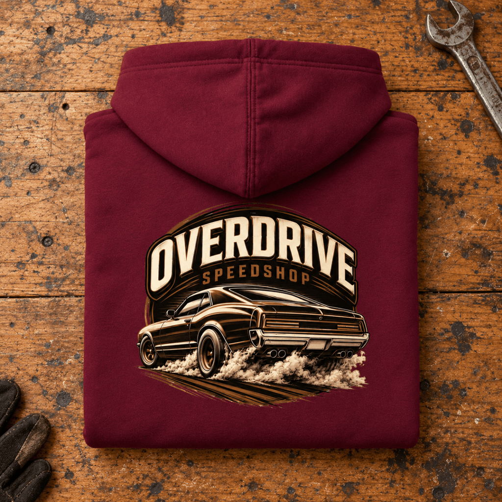 Camberline Muscle Car Graphic Hoodie in burgundy, folded back view on a workshop bench with the full graphic visible