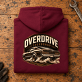 Camberline Muscle Car Graphic Hoodie in burgundy, folded back view on a workshop bench with the full graphic visible