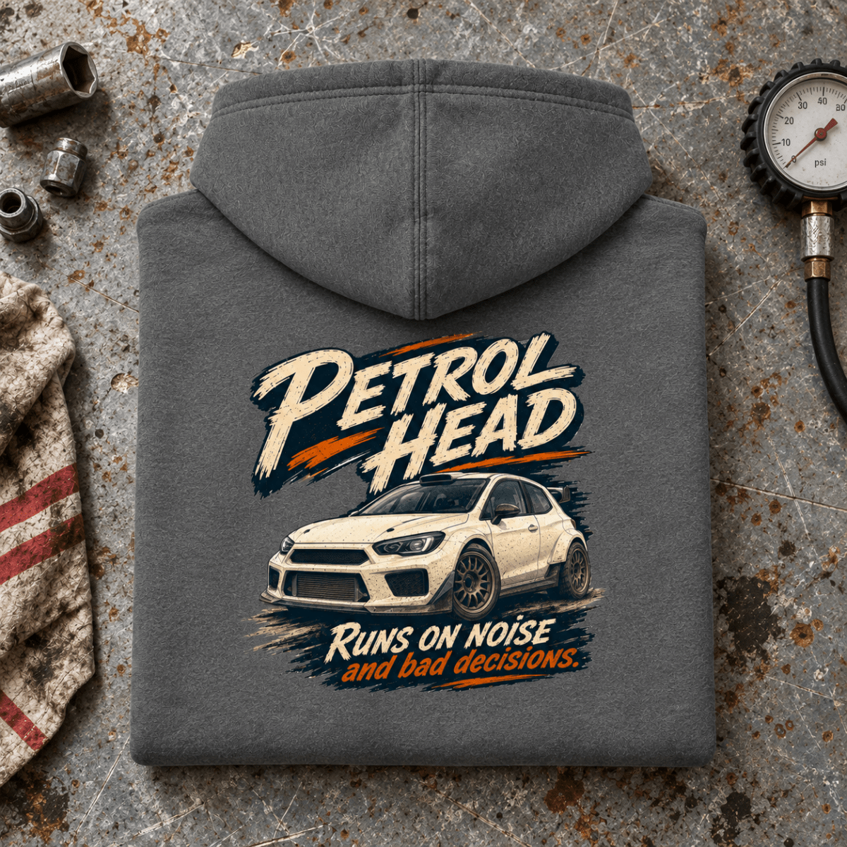 Rally Car Graphic Hoodie – Hatchback Motorsport Charcoal, folded back hero on a worn automotive workbench – car-hd-0077