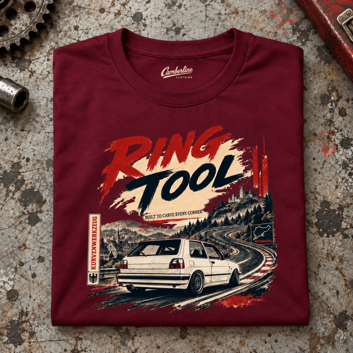 Hot Hatch Graphic T-Shirt – Ring Tool Nürburgring Mk2 Track Day Line Art, folded front main hero on a worn automotive workbench – car-ts-0043