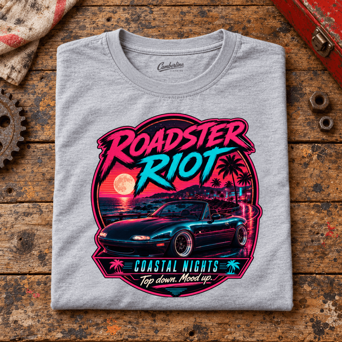 Classic Roadster Graphic T-Shirt – Riot Coastal Nights Top Down, folded front main hero on a worn automotive workbench – car-ts-0047