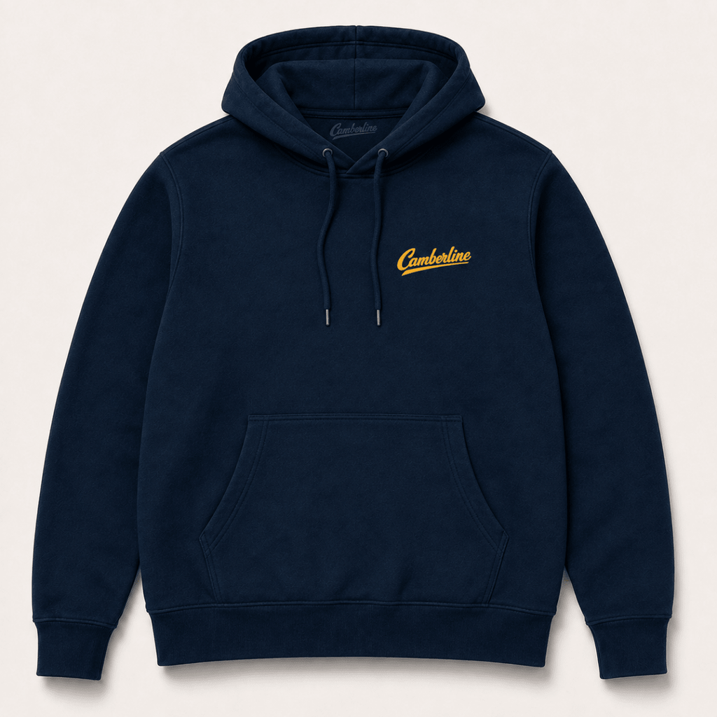 A navy blue pullover hoodie with a small yellow embroidered 'Cumberland' logo on the left chest, displayed against a light beige background.