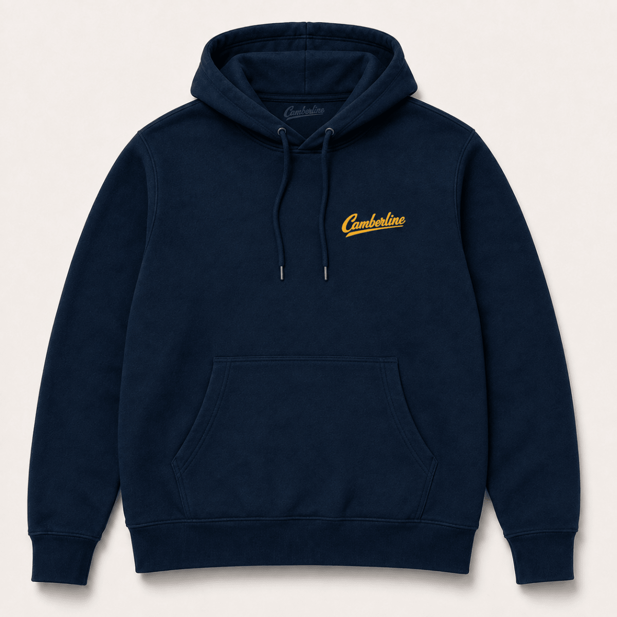A navy blue pullover hoodie with a small yellow embroidered 'Cumberland' logo on the left chest, displayed against a light beige background.