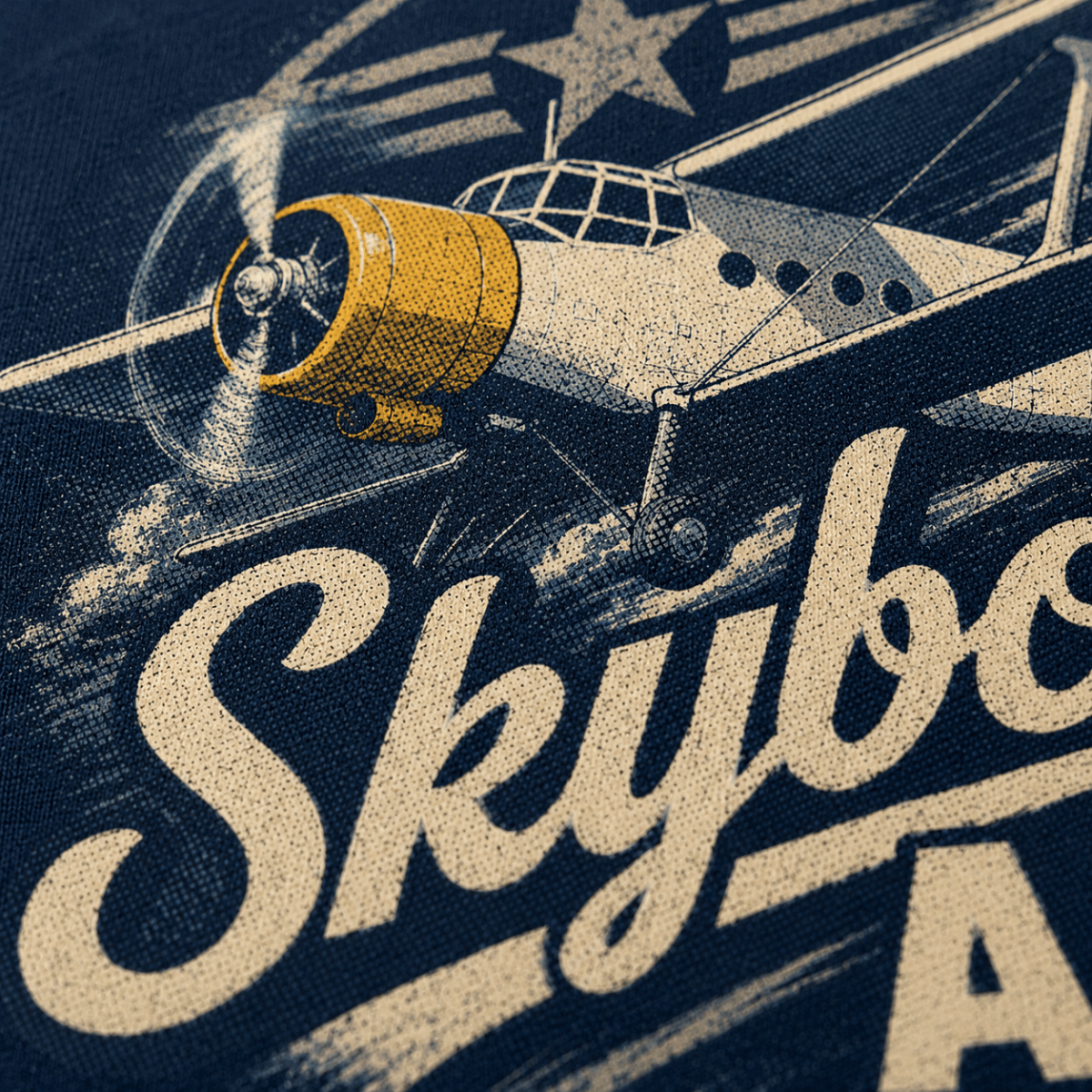 Close-up of a navy graphic print featuring a vintage airplane with a yellow engine and large cream lettering that reads 'Skybo.