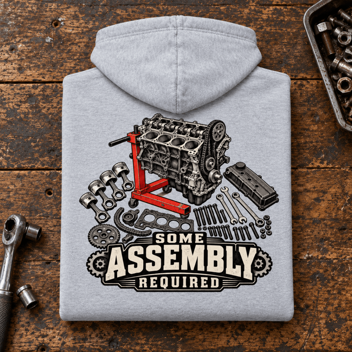 Camberline Engine Rebuild Mechanic Hoodie in heather grey, folded back view on a workshop bench with full graphic visible