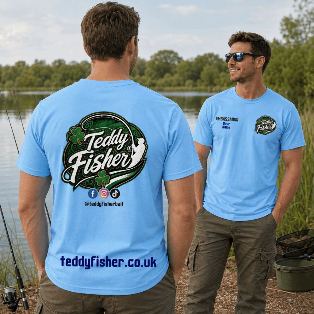 Two men standing outdoors by a lake wearing light blue custom graphic T-shirts. The man on the left shows the back of the shirt with a large 'Teddy Fisher' logo and website text, while the man on the right shows the front chest logo.