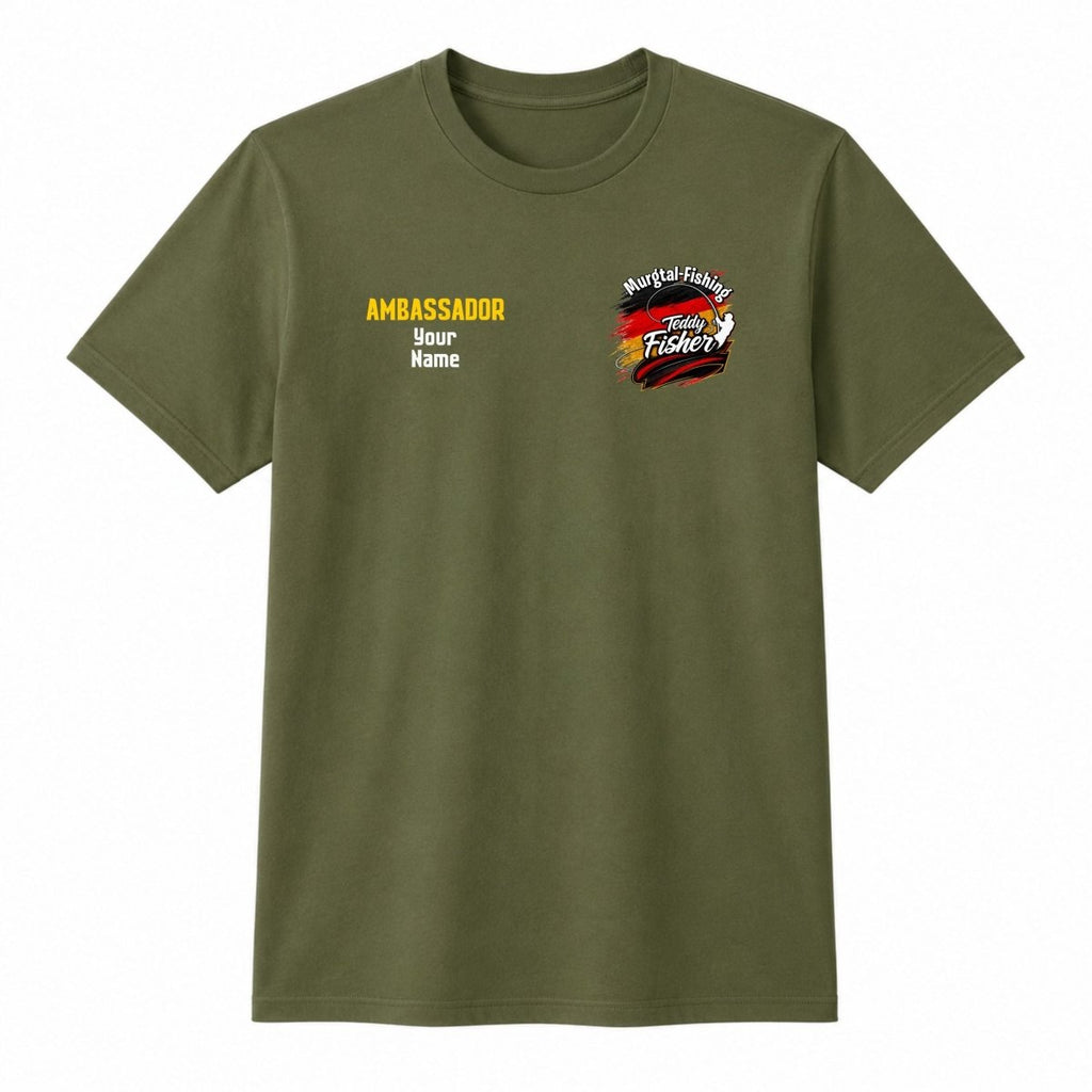 An olive green short-sleeve t-shirt with custom printed graphics on the chest. The left chest features the text 'AMBASSADOR' in yellow, followed by 'Your Name' in white.