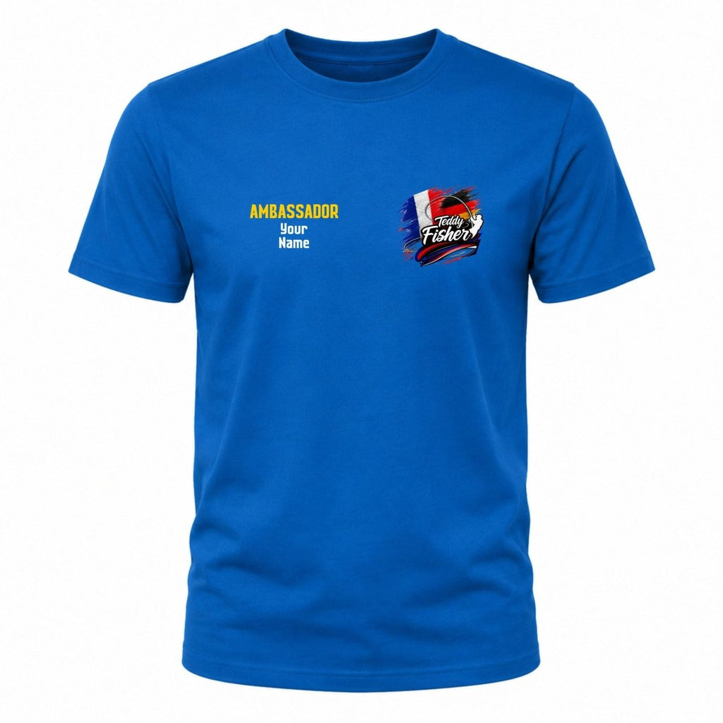 A royal blue short-sleeve crewneck t-shirt with a customizable graphic on the left chest. The graphic features yellow and white text reading 'AMBASSADOR Your Name' alongside a colorful 'Angry Fisherman' logo.