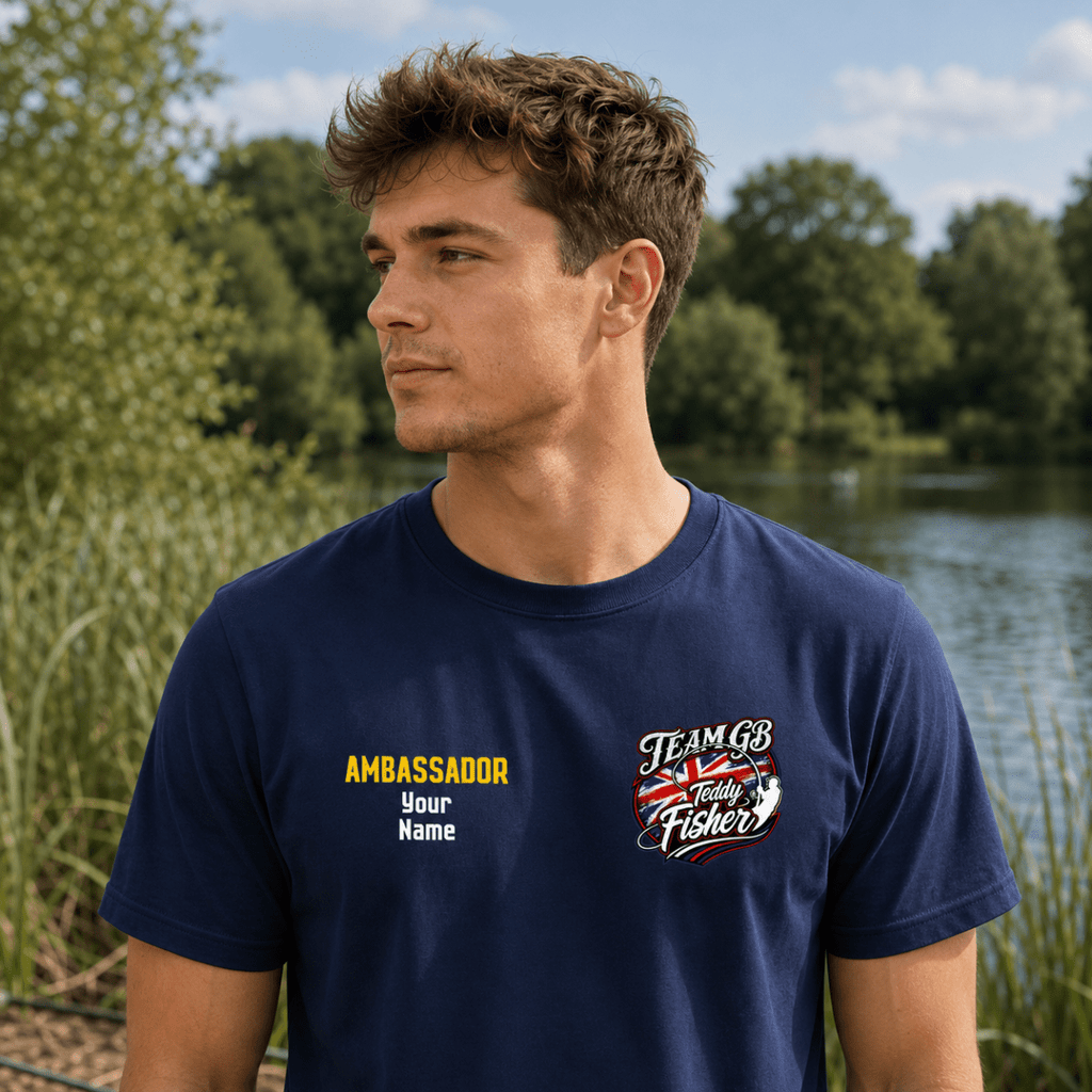 A man wearing a navy blue t-shirt with custom printed graphics, standing outdoors near a lake with trees in the background.