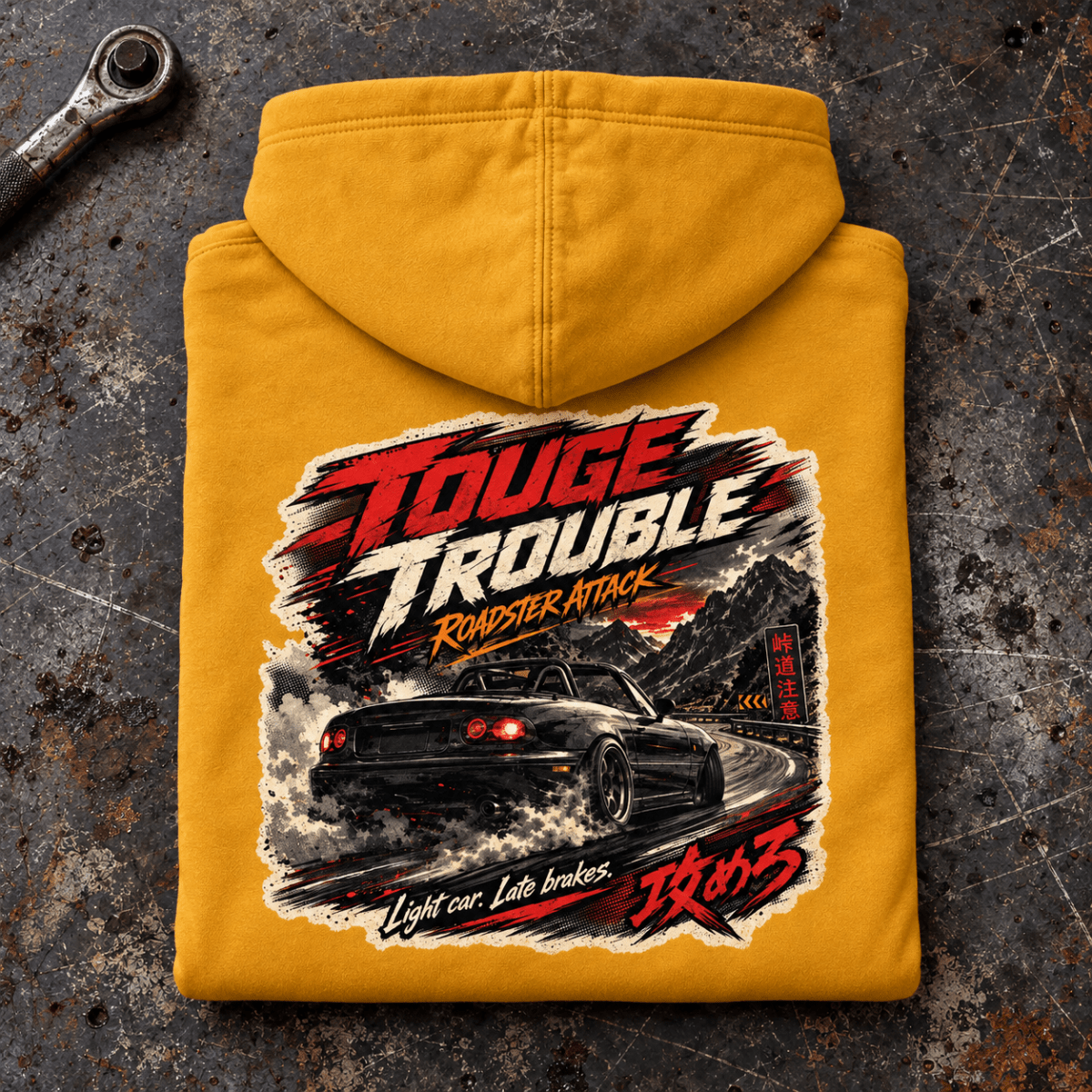 Folded mustard Touge Trouble roadster hoodie, rear print on a scratched tuning bench — car-hd-0049