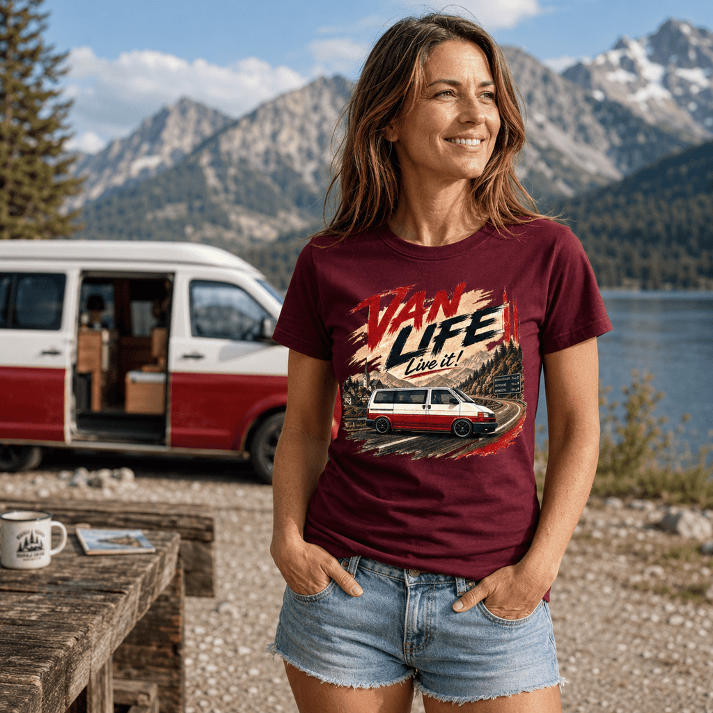 Woman wearing a 'Van Life Live It' t-shirt with a van and nature graphic, standing in front of a scenic lake and mountains.